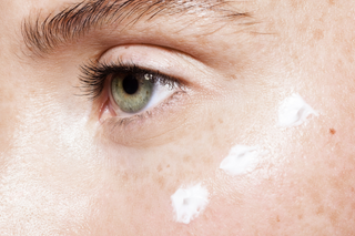 Close-up of a person's eye with a By Nature eye cream applied to the skin.