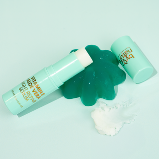 By Nature Aloe Vera and Vitamin E serum stick leaning on jelly, next to a swatch of serum on a light blue background