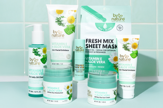 Collection of skincare products with 'by nature' branding against a light blue tiled wall. Vitamin E and Aloe Vera range.